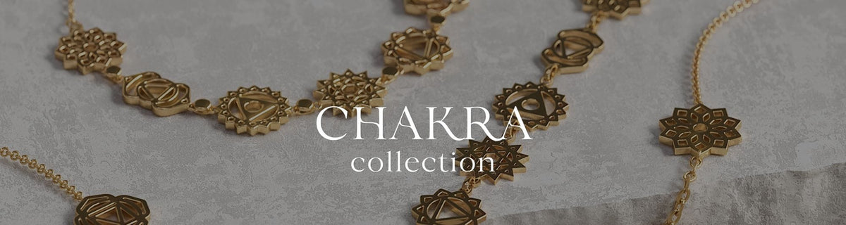 Gold chakra jewelry from the Daya Chakra Collection styled on a stone surface